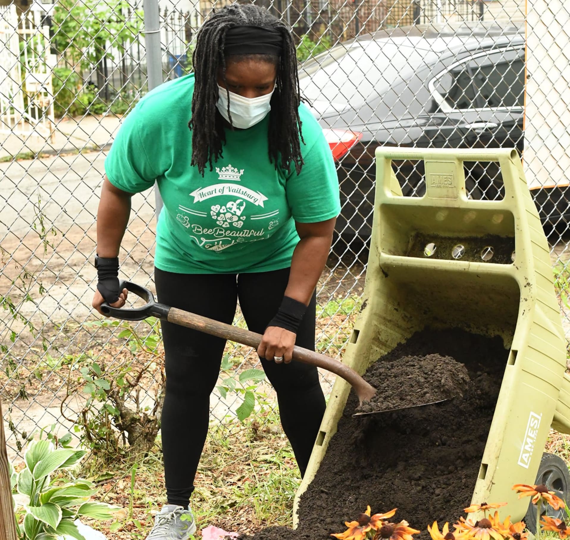 A woman wearing a mask and holding a shovel.